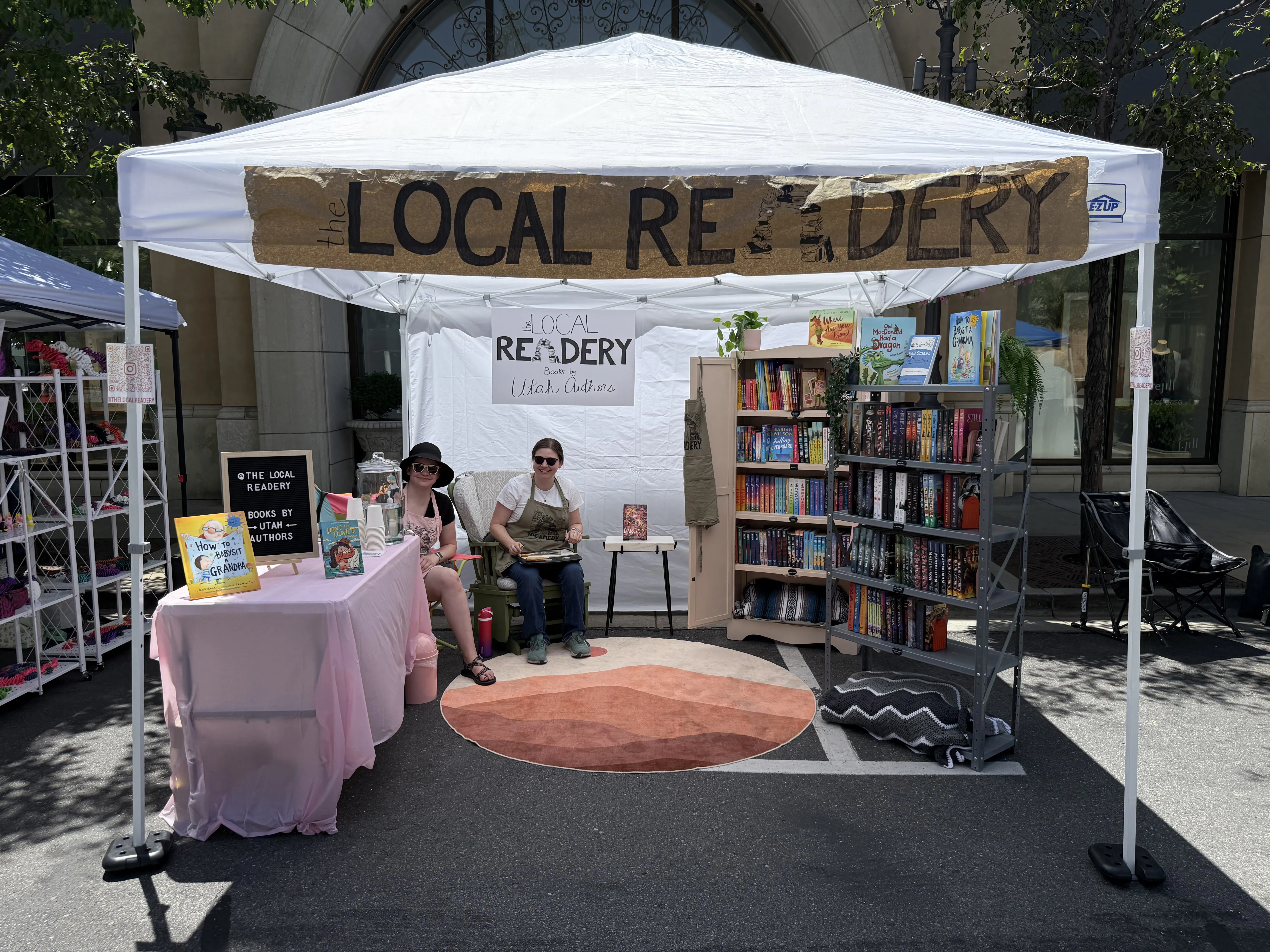 The Local Readery pop-up tent with bookshelves and readers at an outdoor market